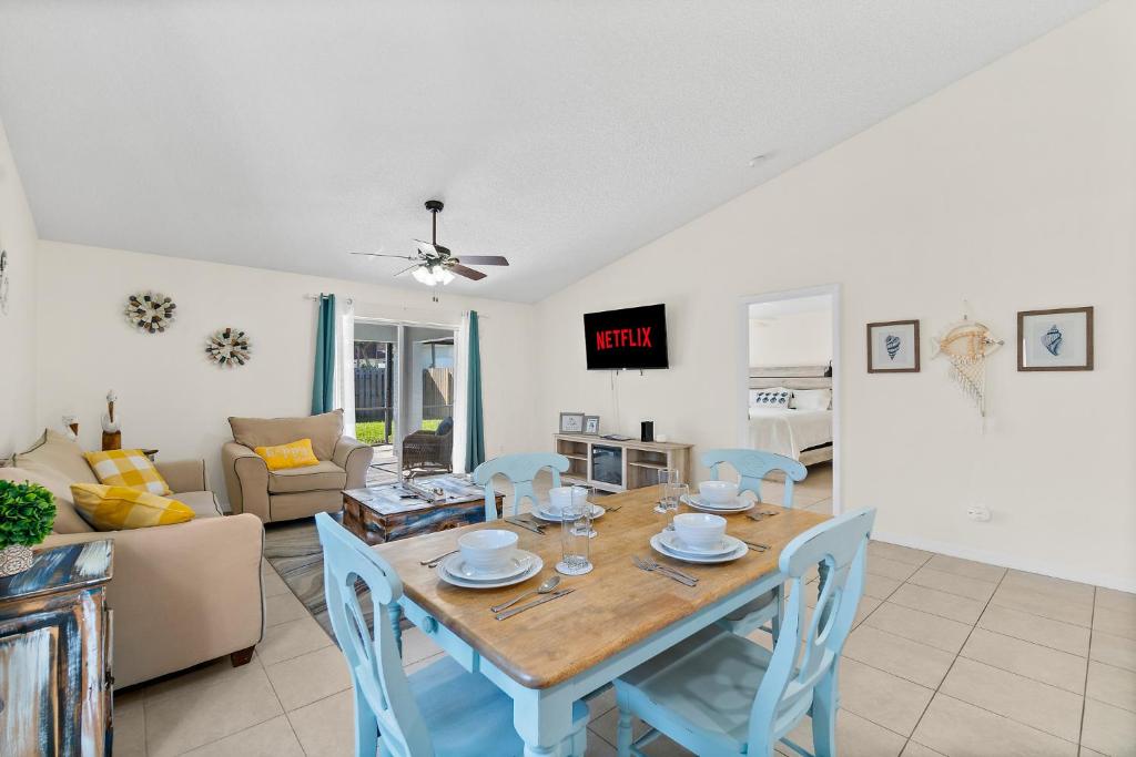 a dining room and living room with a table and chairs at Oceanview Haven - 2BR Beach House with Patio Heated Pool Steps from Paradise Beach Park! in Melbourne
