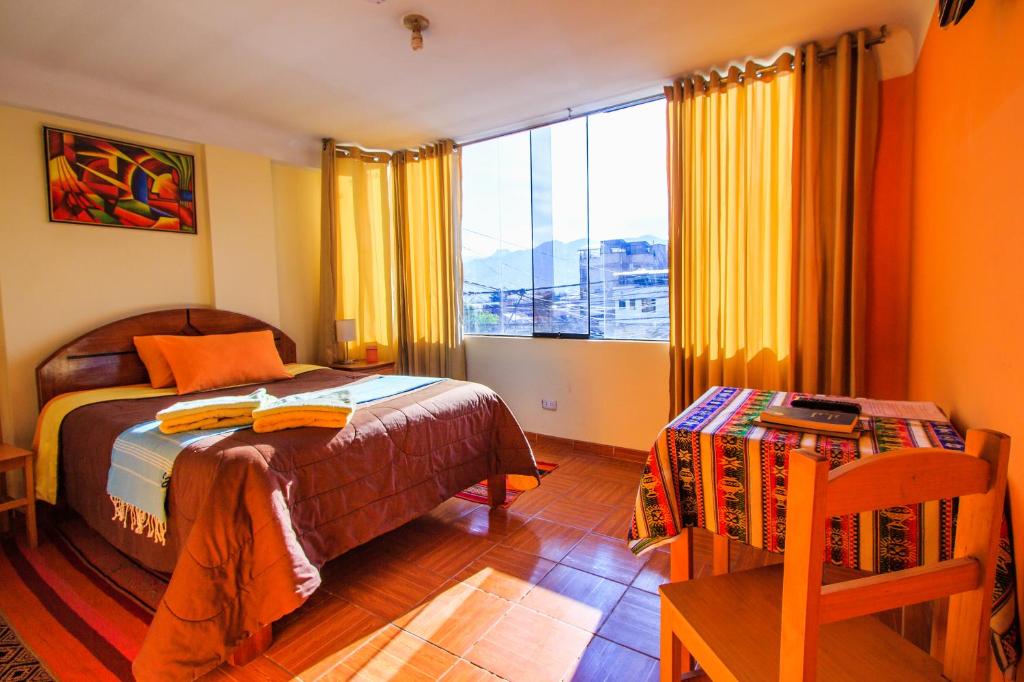 a bedroom with a bed and a table and a window at T'ika Guest House in Cusco
