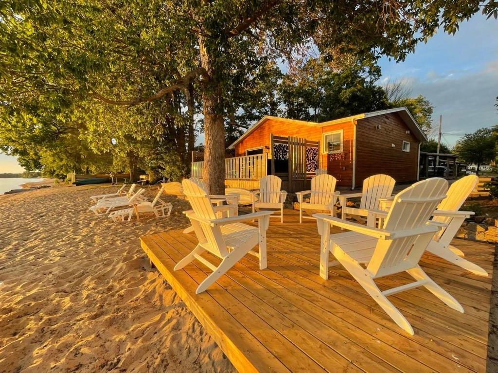 a wooden deck with white chairs and a house at The Finch Beach Resort in North Bay