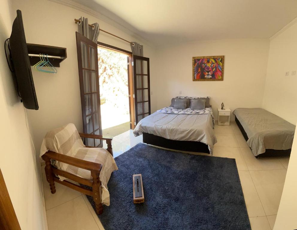1 dormitorio con 2 camas, silla y ventana en Mountain memory, en Campos do Jordão