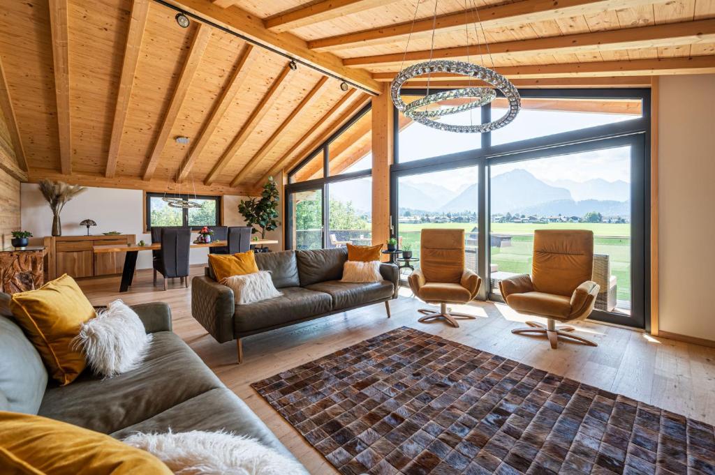 ein Wohnzimmer mit Sofas und Stühlen sowie einem großen Fenster in der Unterkunft Alpine Lifestyle Lodge in Oberstdorf