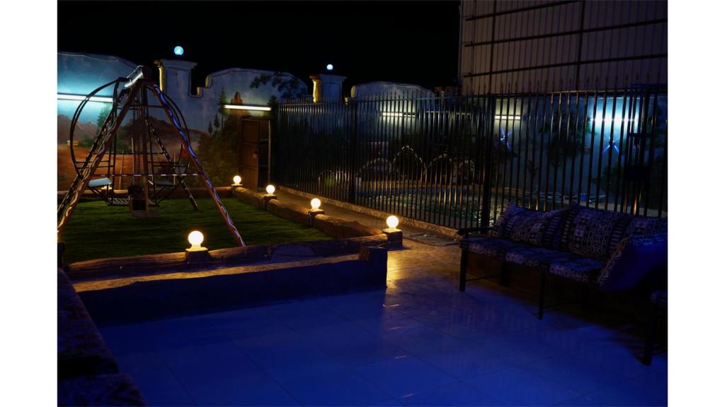 شاليهات دي لا كروز في مكة المكرمة: ملعب في الليل مع مجموعة أرجوحة وأضواء