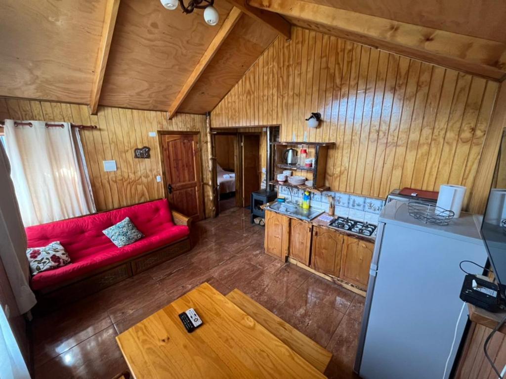 a kitchen with a red couch in a room at Cabañas "El Cazador" in Futaleufú