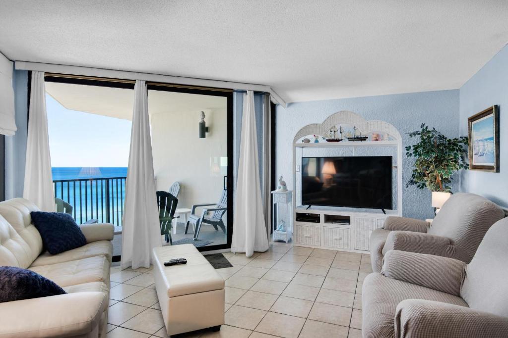 sala de estar con sofá, TV y balcón en Sunbird 1106W en Panama City Beach