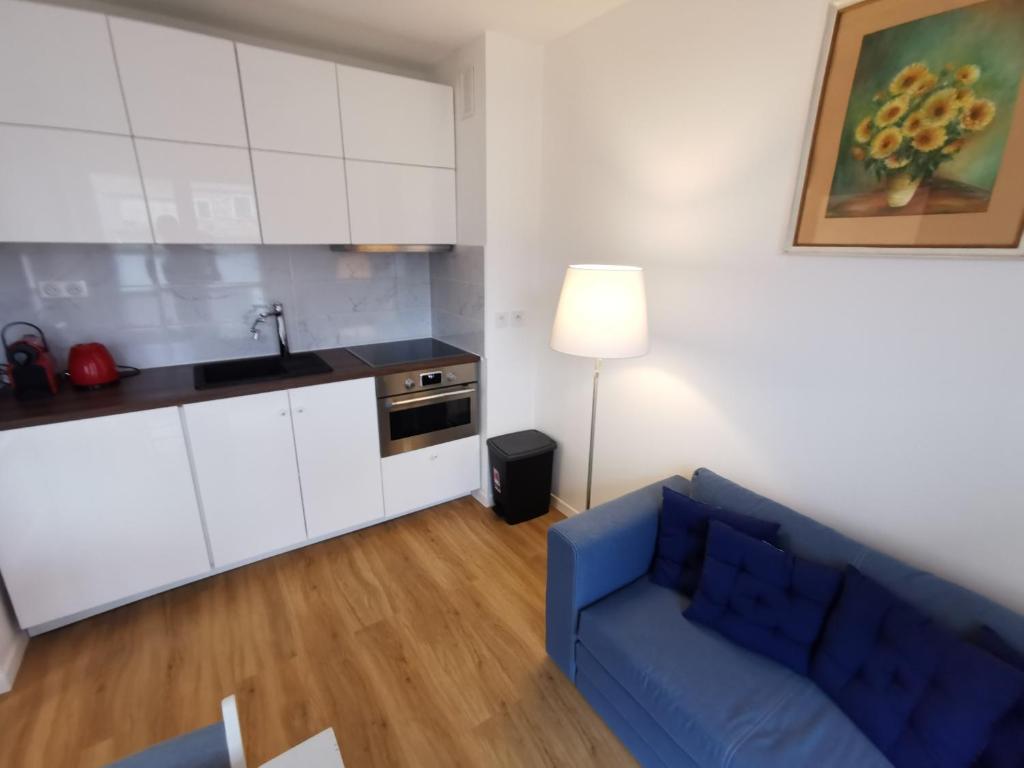 a living room with a blue couch and a kitchen at Charming apartment Chambourcy in Chambourcy