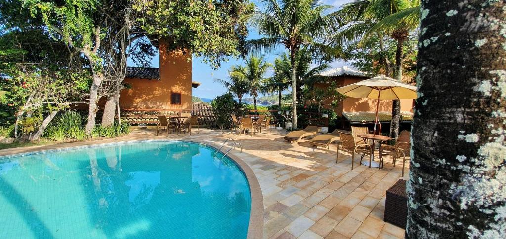 uma piscina com uma mesa e um guarda-sol em Casa Praia do Forno Búzios, condomínio, 3 quartos em Búzios
