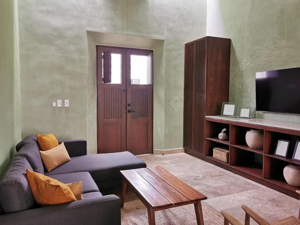 a living room with a couch and a table and a tv at Casa Mara 53 Luxury House in downtown Mérida in Mérida