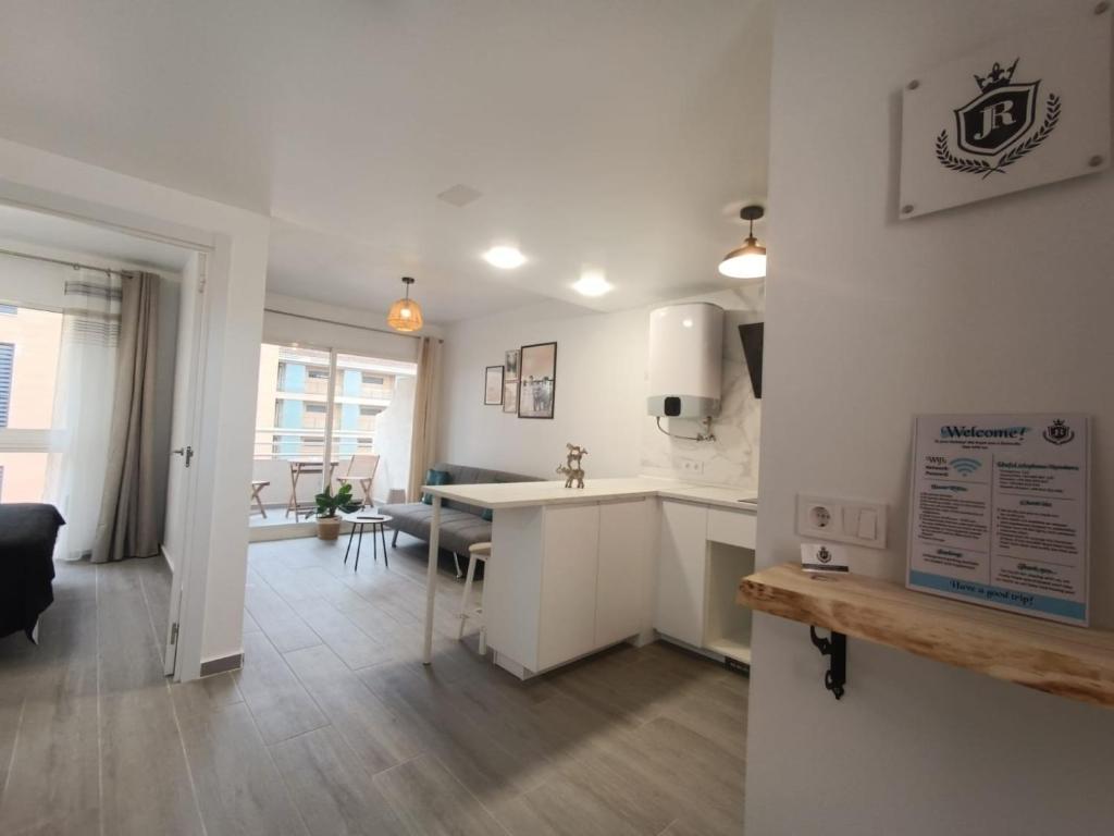 een keuken en een woonkamer met witte kasten en een tafel bij JR apartment albir in Albir
