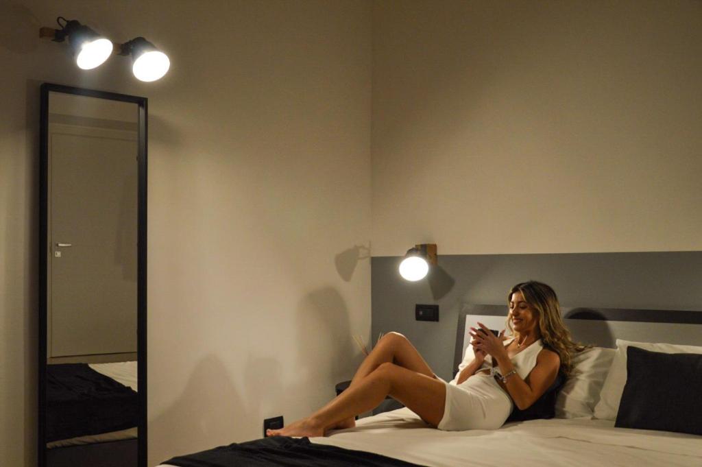 Kobieta siedząca na łóżku patrząca na komórkę w obiekcie B&B Piani Diversi w mieście Altamura