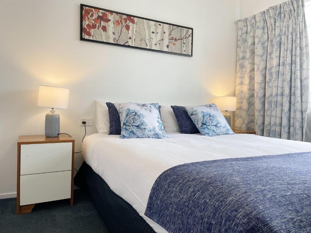 a bedroom with a large bed and a nightstand with a bed sidx sidx sidx at Pupuke Manor Motel in Auckland