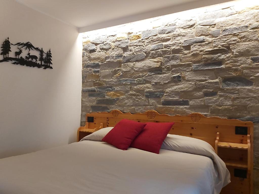 1 dormitorio con 1 cama con pared de piedra en La petite maison, en La Thuile