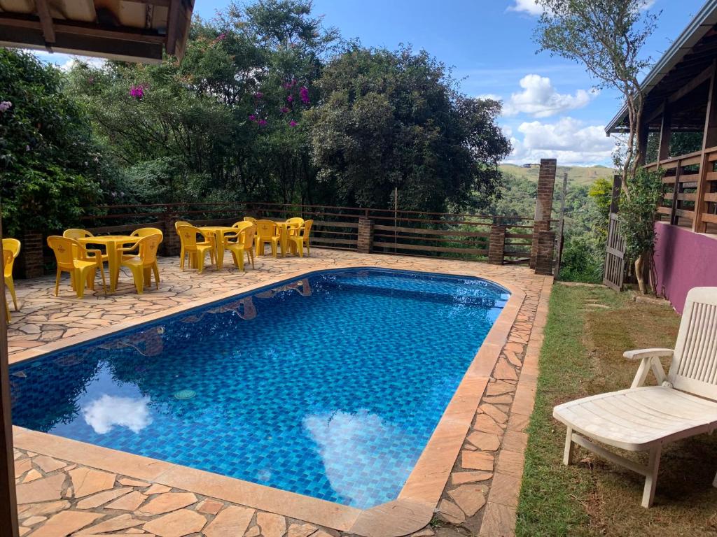 a swimming pool with yellow chairs and a table at Pousada Evolucao in Macacos