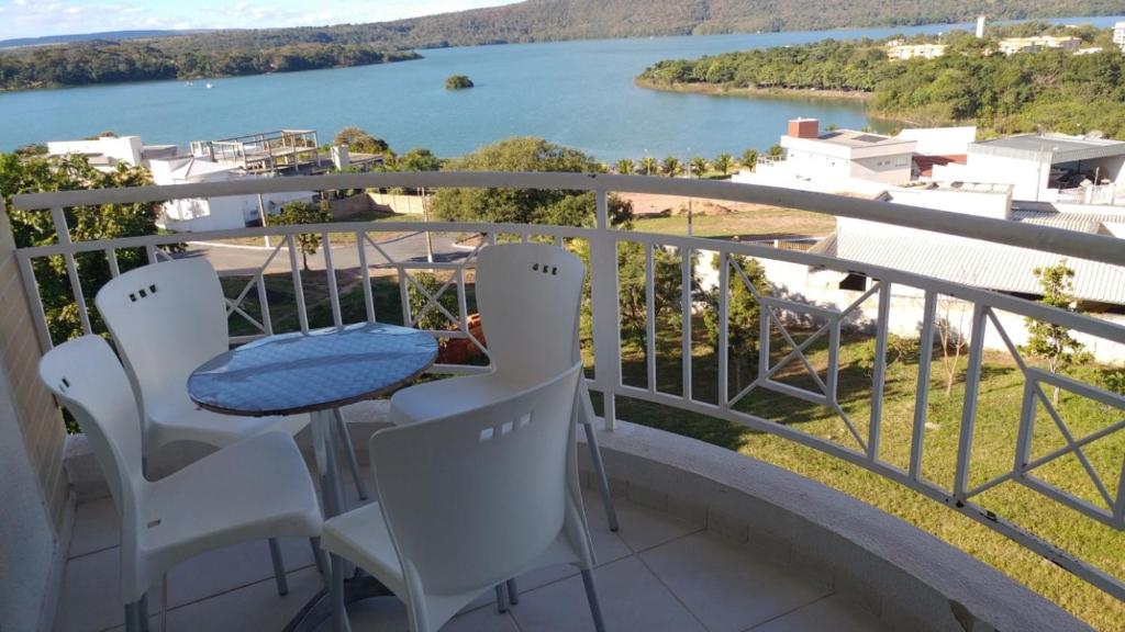 balcón con mesa, sillas y vistas al agua en Apartamento encantador de frente ao lago Corumbá, en Caldas Novas