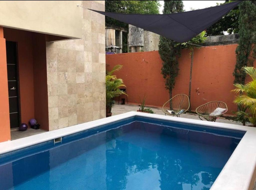 una piscina en un patio trasero con una sombrilla negra en ALCOBY APARTMENT, en Cancún