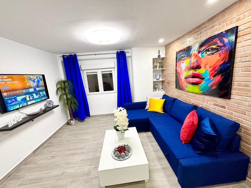 a living room with a blue couch and a tv at Rambla Apartment by the Sea in Alicante