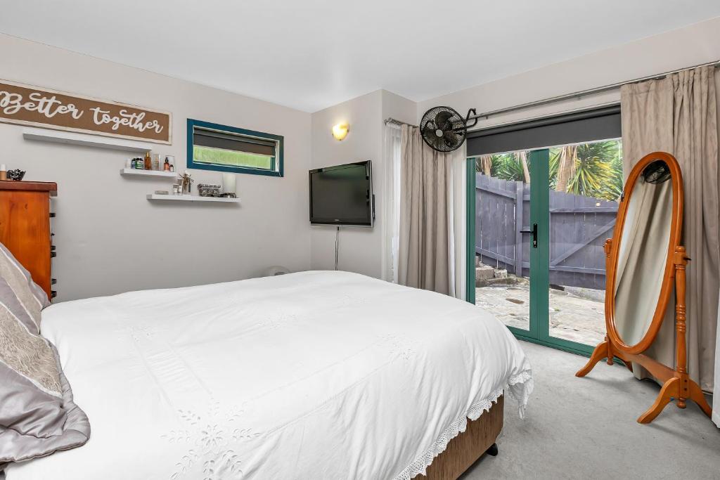 a bedroom with a bed and a mirror and a window at Mi Castillo on Hatea Drive in Whangarei