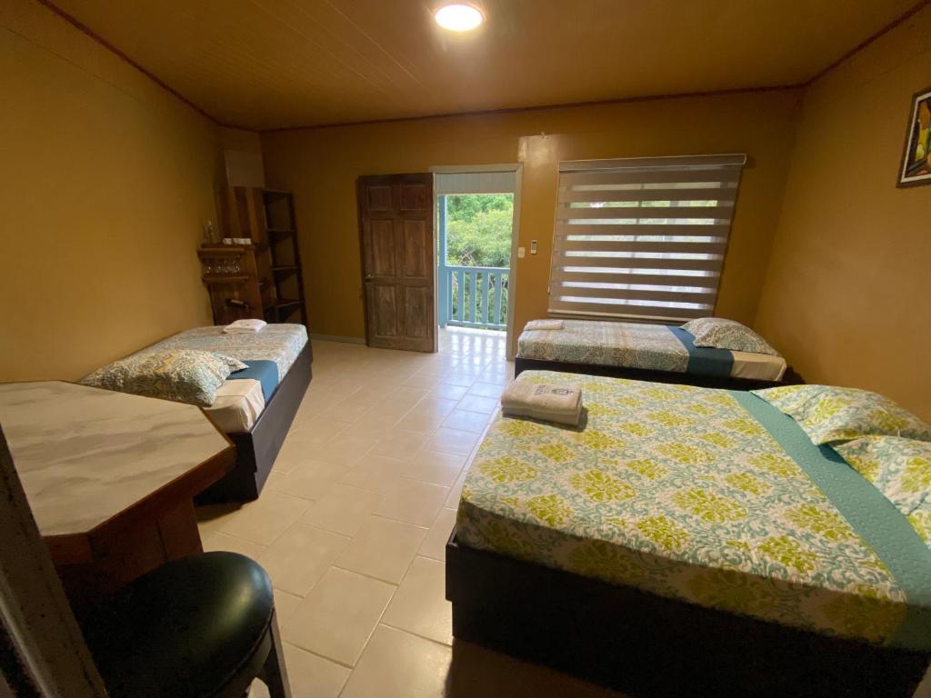 モンテスマにあるHotel Ticozumaのベッド3台、テーブル、窓が備わる客室です。