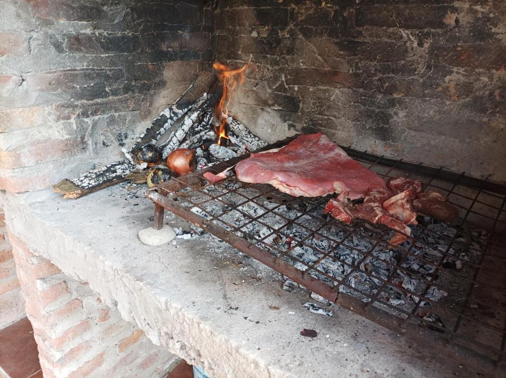 un horno de ladrillo con carne y fuego en él en El paraíso de lupe en San Javier
