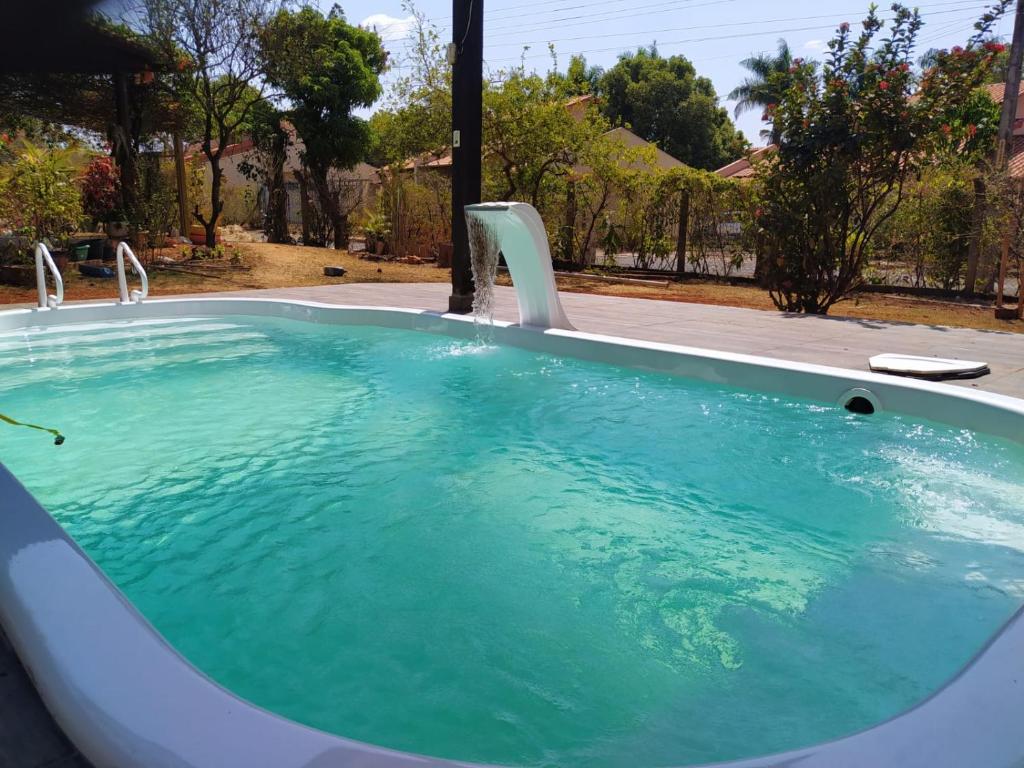 Casa em Caldas - PISCINA SOLAR E ELETRICA في كالدس نوفاس: حوض استحمام ساخن في الفناء الخلفي مع المياه الزرقاء