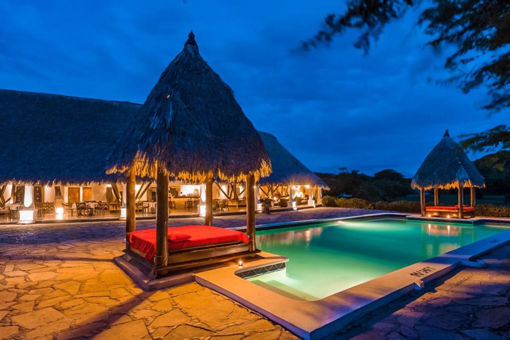 a resort pool with a bed and thatched umbrellas at Hotel Punta Teonoste in Popoyo