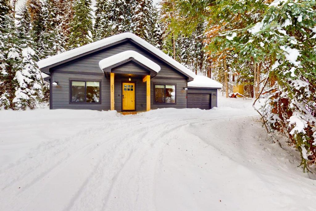 een klein huis met een gele deur in de sneeuw bij Sleepy Hollow in Donnelly