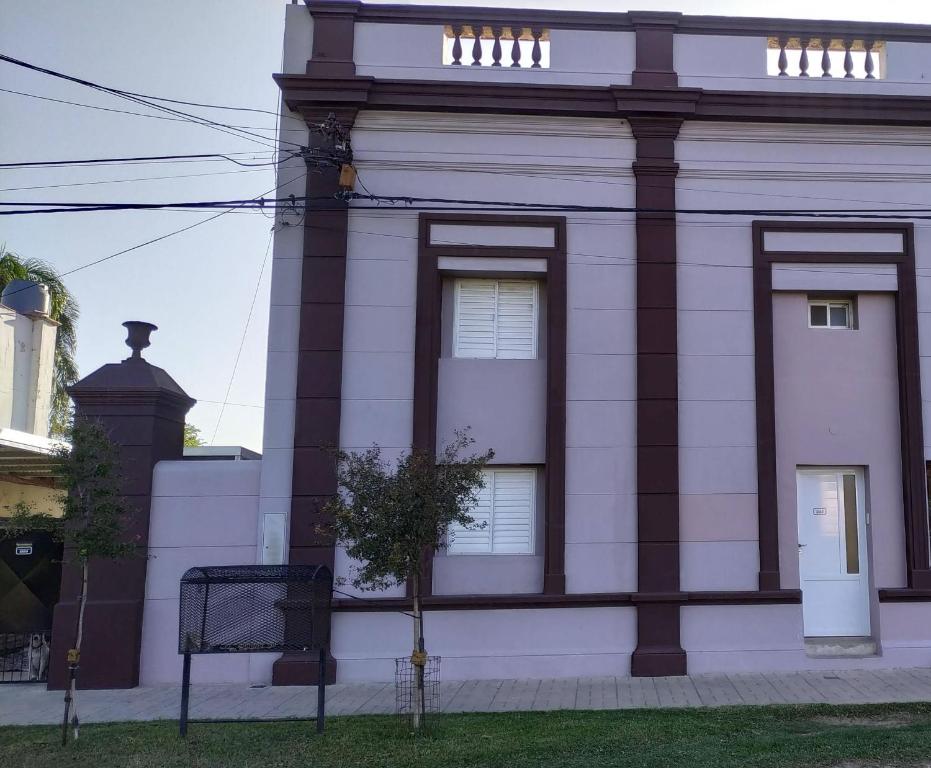 a white building with a tree in front of it at Don Oscar Alojamientos Dpto Lenna in San Justo