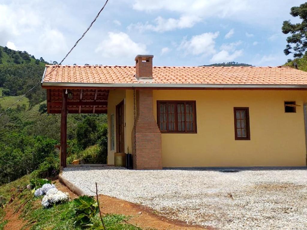 a small yellow house with a roof at Chalé Som do Riacho com Hidromassagem e Lareira á 20 minutos de Gonçalves mg in Gonçalves