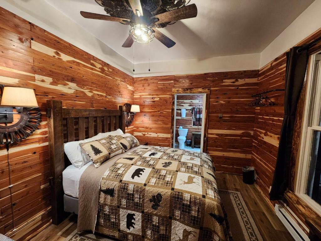 een slaapkamer met een bed en een plafondventilator bij Log Cabin Inn in Eureka Springs