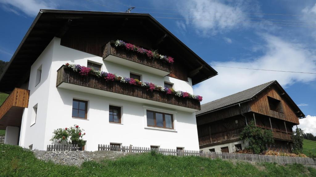 une maison blanche avec un toit noir et des fleurs dans l'établissement Rieserhof, à Heinfels