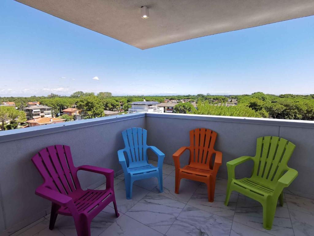 4 farbenfrohe Stühle auf einem Balkon mit Aussicht in der Unterkunft Studio in San Michele al Tagliamento 42856 in San Michele al Tagliamento