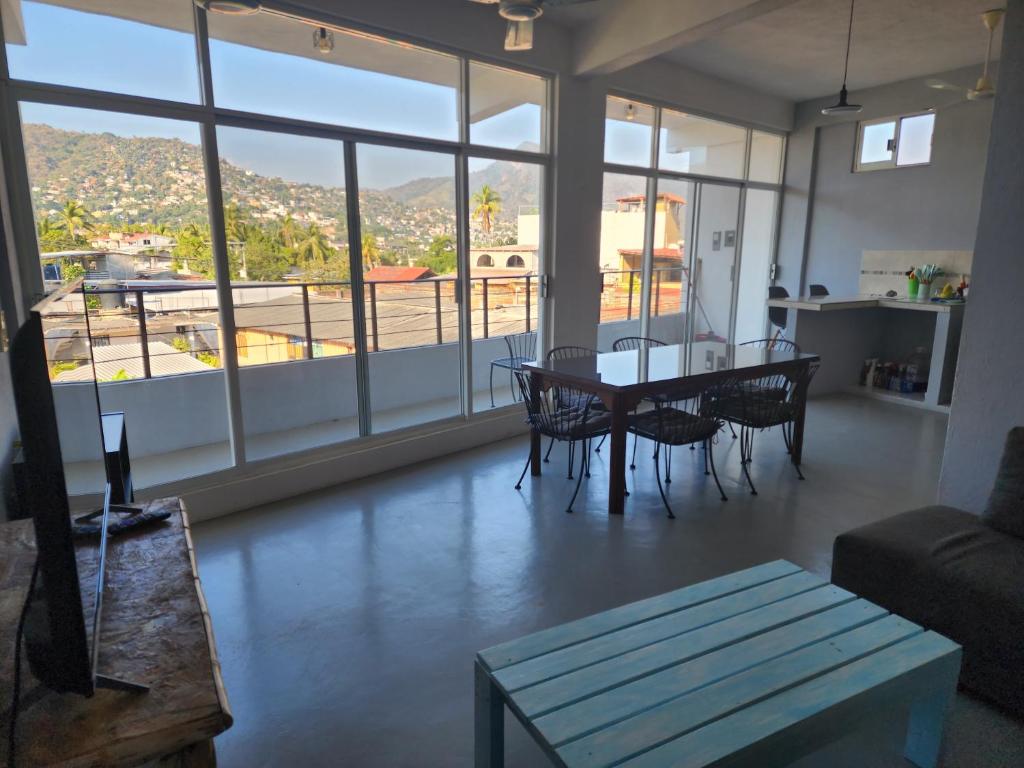 - un salon avec une table, des chaises et une grande fenêtre dans l'établissement Large and comfy apartment, near DT and Principal Beach!, à Zihuatanejo