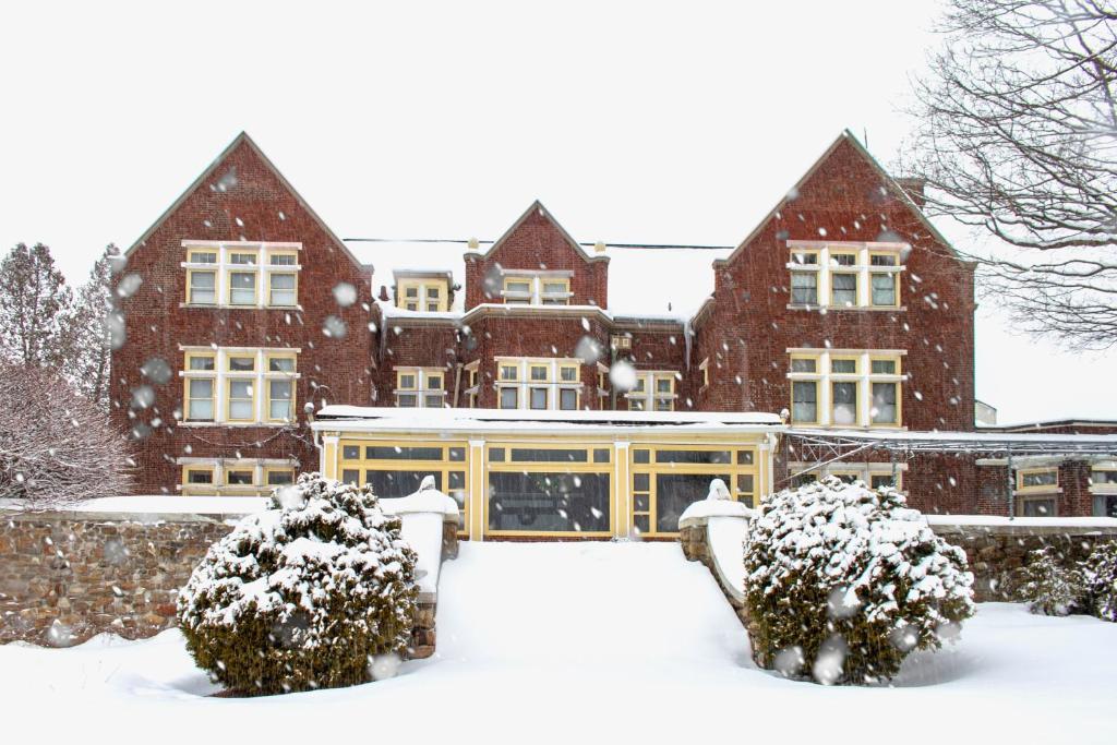 un edificio cubierto de nieve con arbustos delante en Wilburton Inn, en Manchester