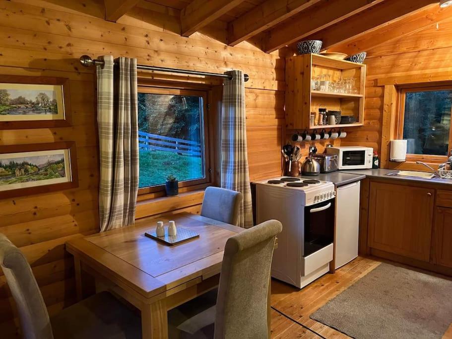 a kitchen with a table and a stove in a cabin at Riverside Lodge in Killiecrankie in Bridge of Tilt