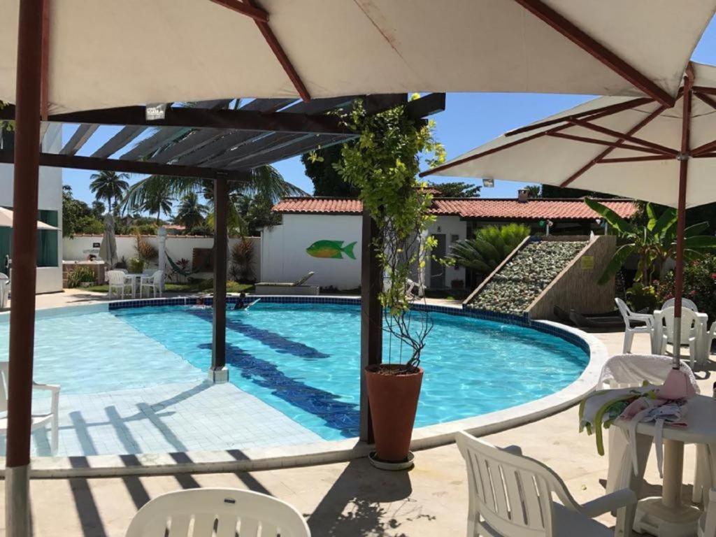einen Pool mit Sonnenschirm und Stühlen in der Unterkunft Mandakaru Residence Flat da Isa 01 in Porto De Galinhas