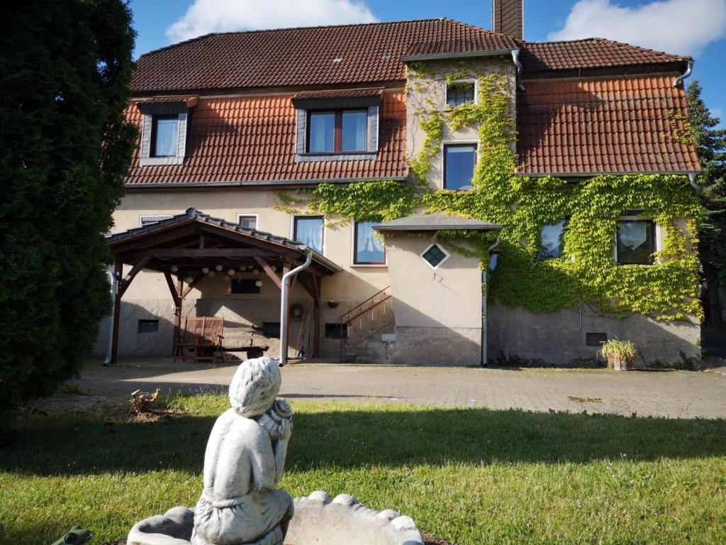 a statue in the grass in front of a house at Pension Kirschgarten in Nebra