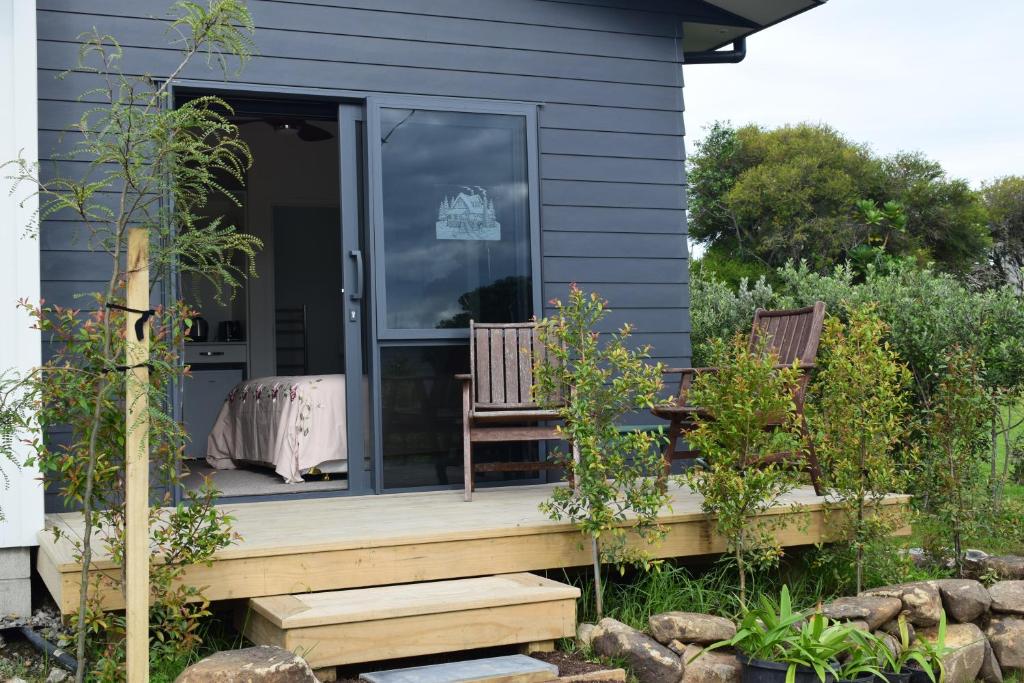 a house with a porch with two benches on it at Paradise In Whitianga B & B in Whitianga