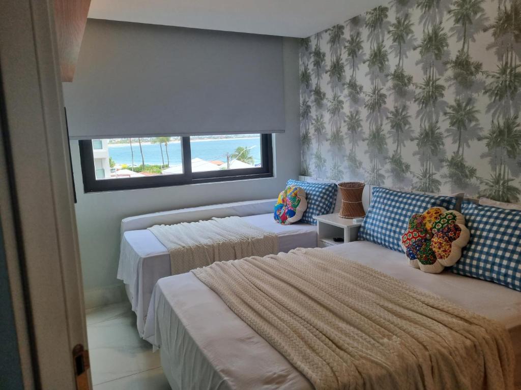 a bedroom with three beds with a view of the beach at PLAGE DU PORTO 204- Beira mar, centrinho turístico in Porto De Galinhas