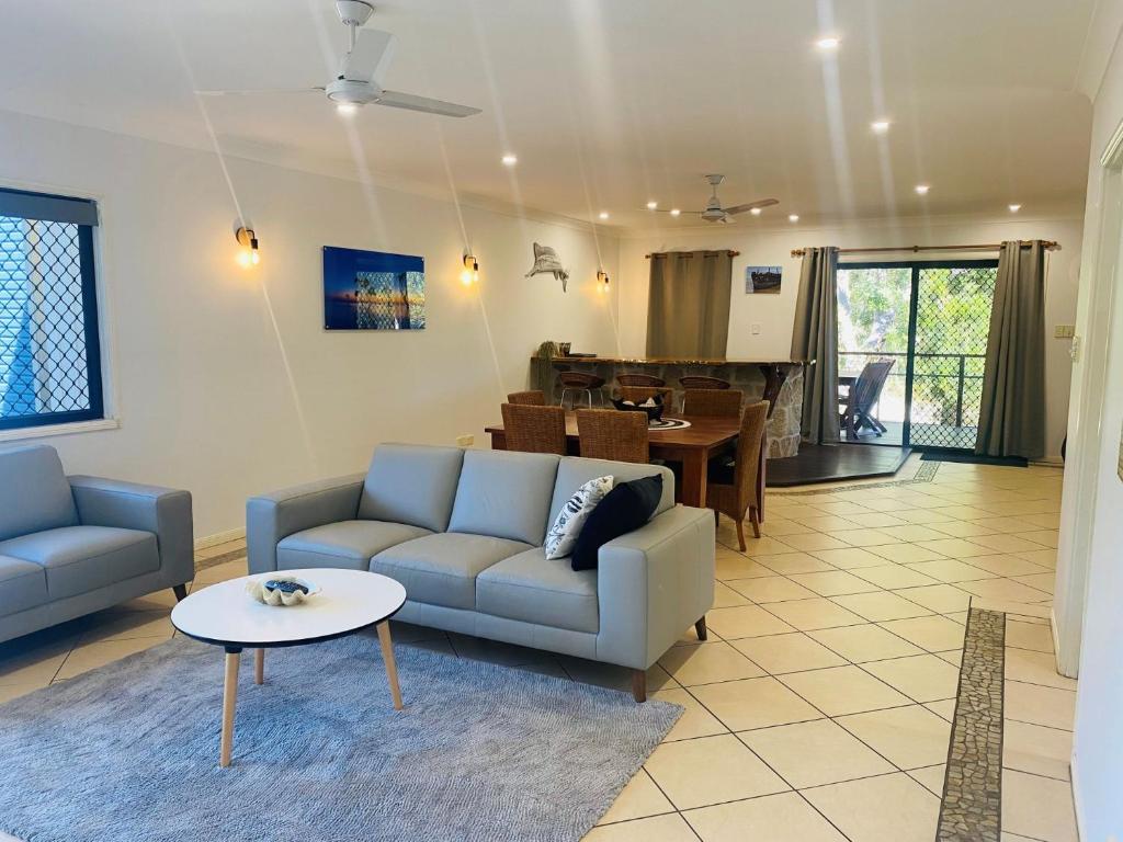 a living room with two couches and a dining room at Sandys On Cypress in Rainbow Beach