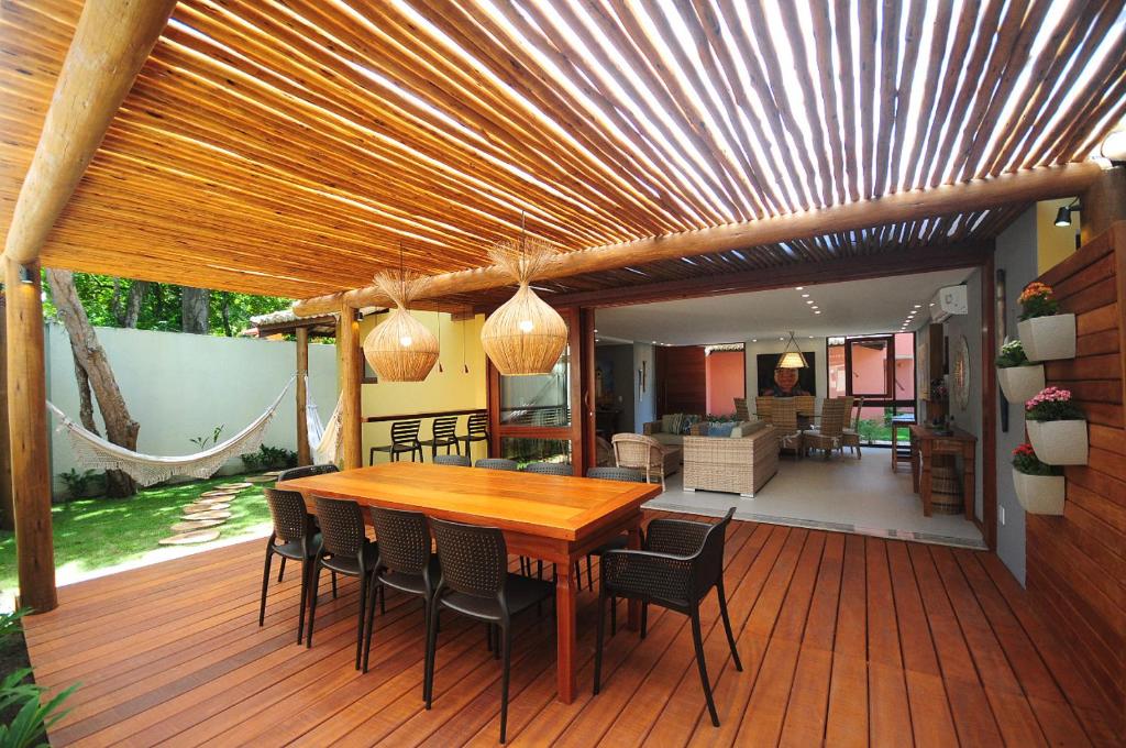 una terraza de madera con mesa y sillas de madera en Casa da Praia Arraial d’Ajuda, vem ser feliz!, en Arraial d'Ajuda