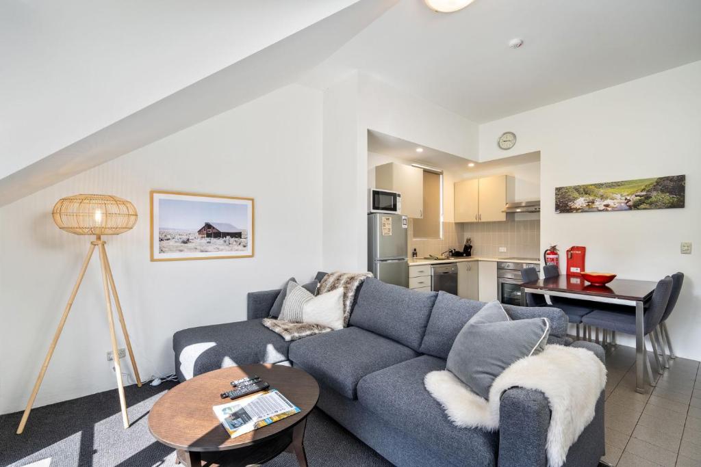 a living room with a blue couch and a table at Lantern 1 Bedroom Balcony with Sweeping Mountain View in Thredbo