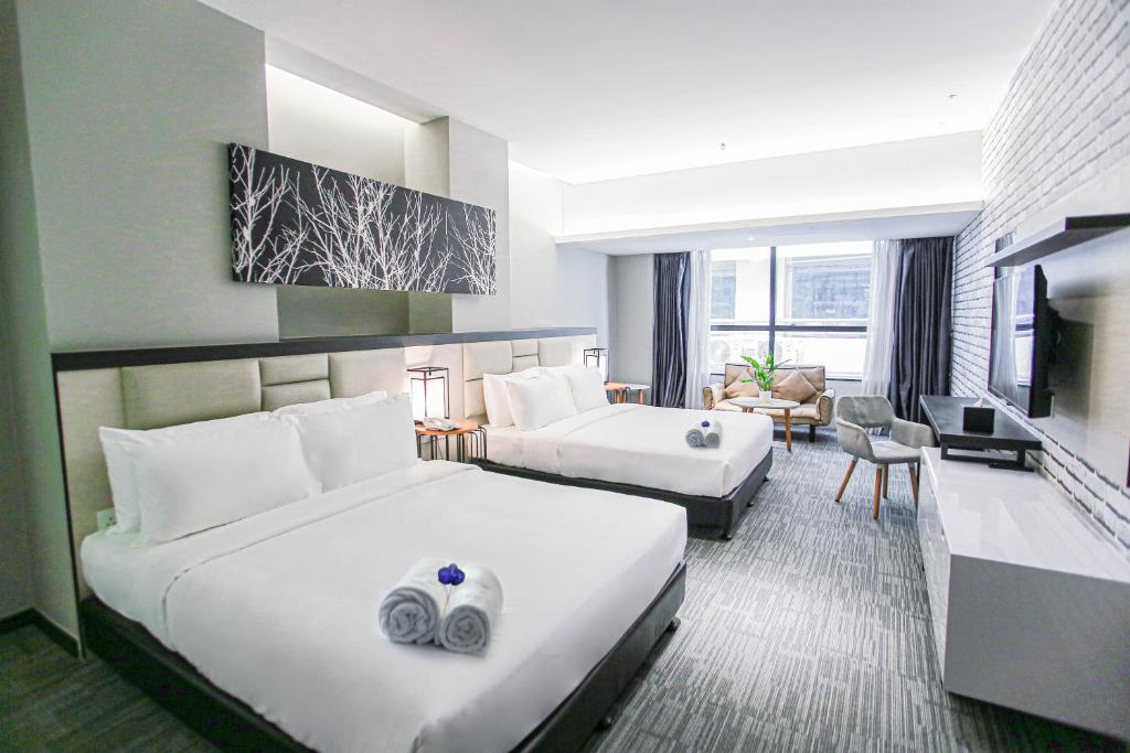 a hotel room with two beds and a living room at Fives Hotel DNP in Johor Bahru