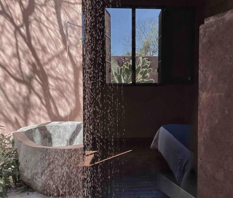 Quinta Amores alojamiento في سان ميغيل دي الليندي: حوض استحمام في غرفة مع نافذة