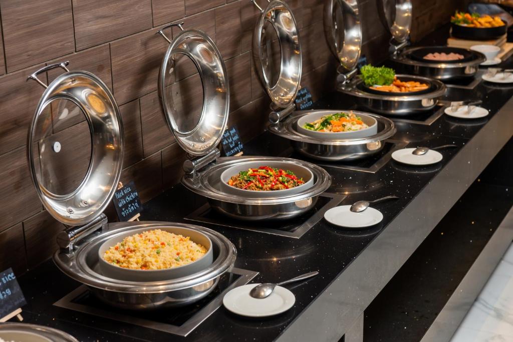 A hot-food buffet displays several covered dishes along a dark stone counter.