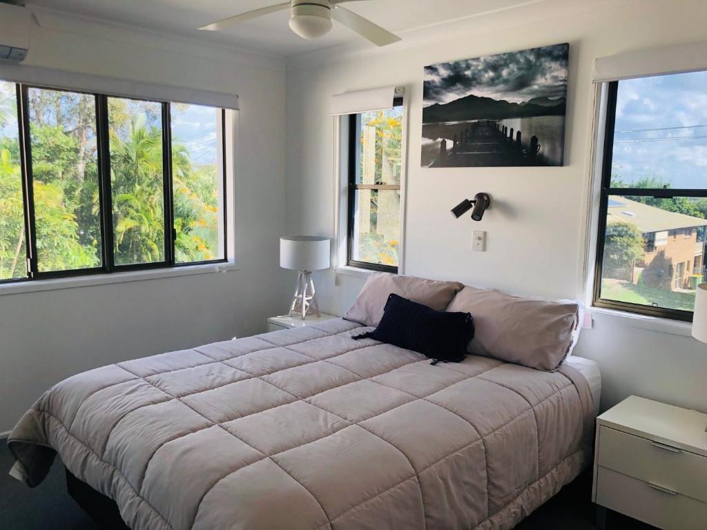 a bedroom with a large bed with windows at Rainbow Stairs in Rainbow Beach