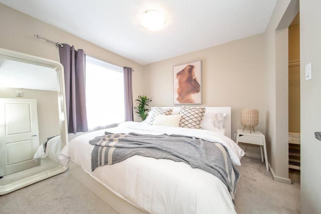 a bedroom with a large bed and a window at Trendy Windermere Condo, AirCon, Top Floor, King Bed, Secure UG Parking, BBQ! in Edmonton