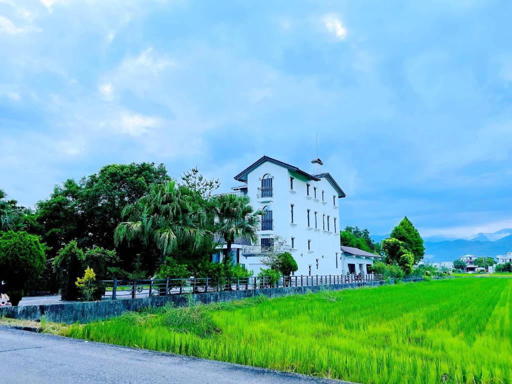 una casa blanca en una colina con un campo verde en Landay Homestay, en Yilan City