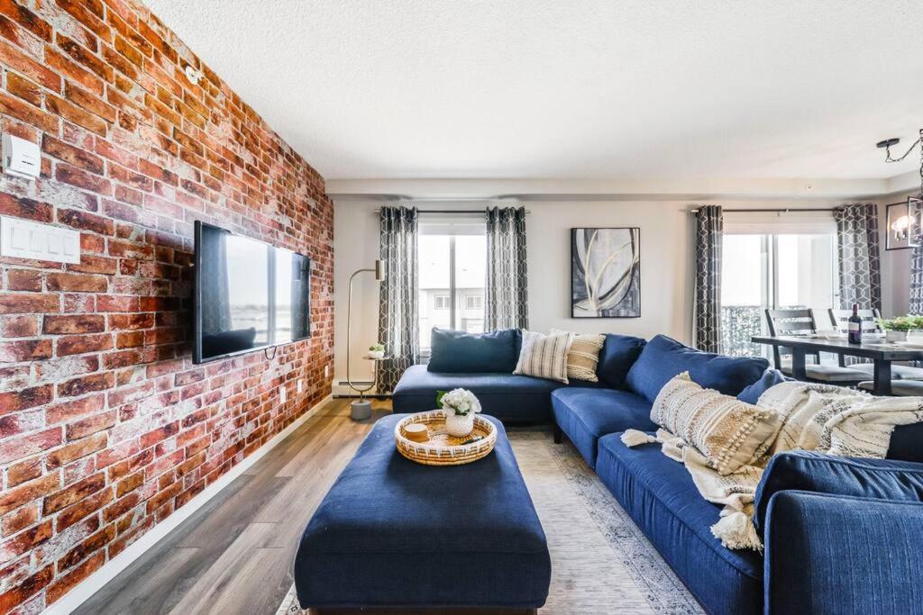 a living room with a blue couch and a brick wall at Bright Luxe Condo, AC, Top Floor, King Bed, Balcony! in Edmonton