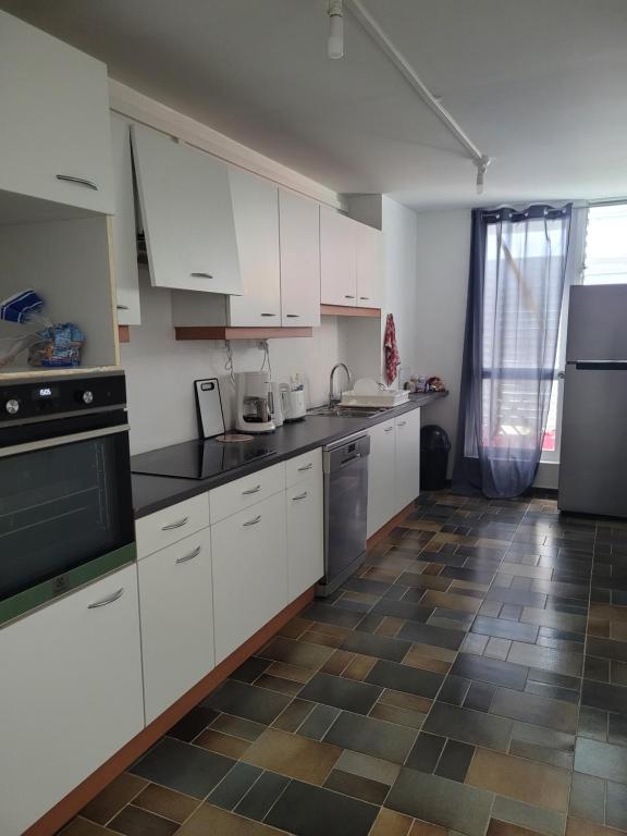 uma cozinha com armários brancos e piso em azulejo em Le 9ème étage du bonheur em Pointe-à-Pitre