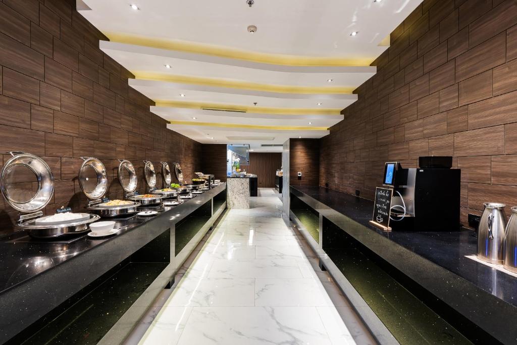 A buffet corridor with covered serving dishes, drinks equipment and dark wood walls.