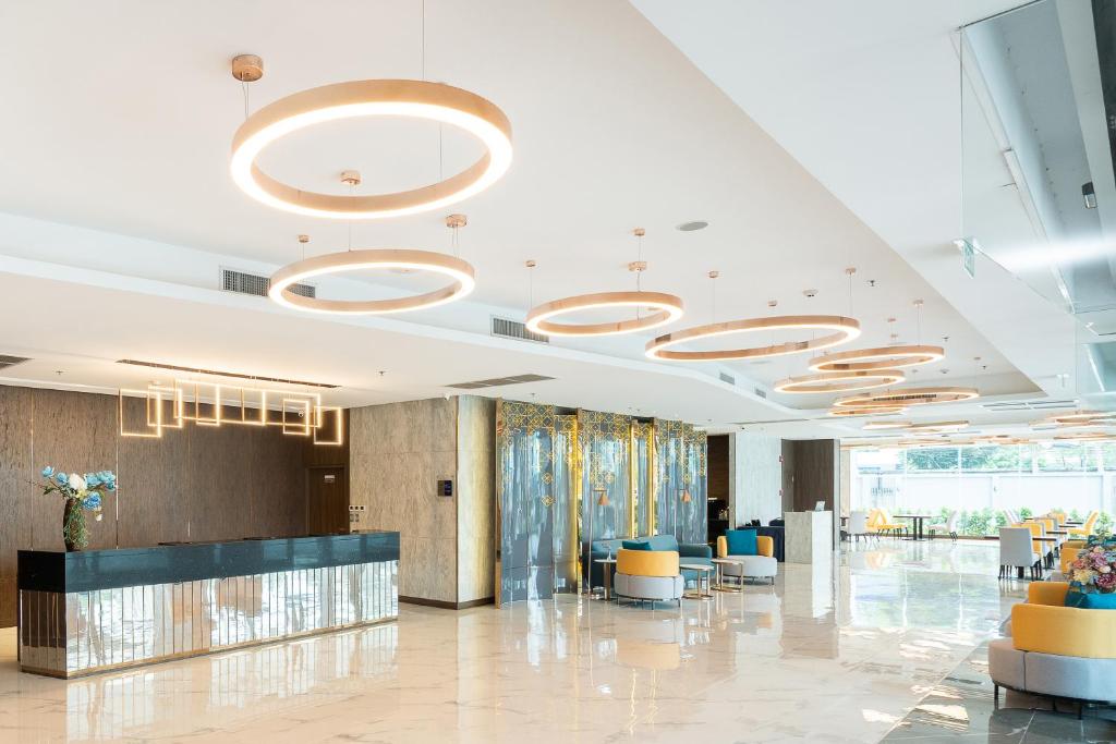 A spacious lobby with a dark reception desk, circular lights and bright seating areas.